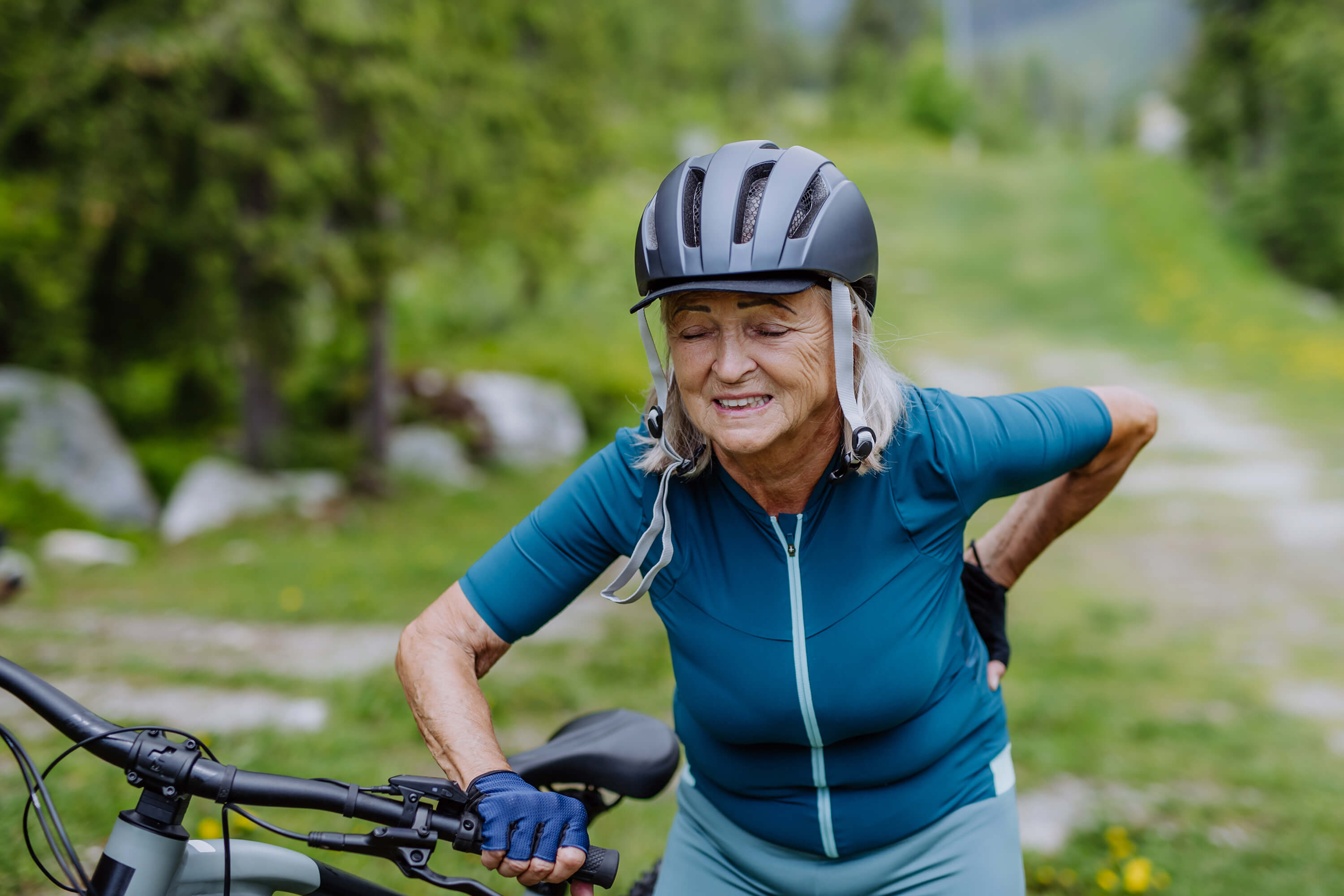 Older bicyclist holding back in pain.