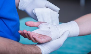 A medical personnel wrapping someone's wrist wound.