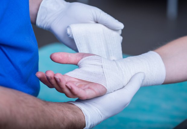 A medical personnel wrapping someone's wrist wound.